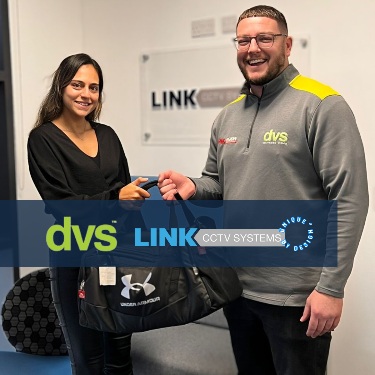 A photo in the Link CCTV office of ryan from DVS handing over Zarina from link a bag for what's in the bag challenge